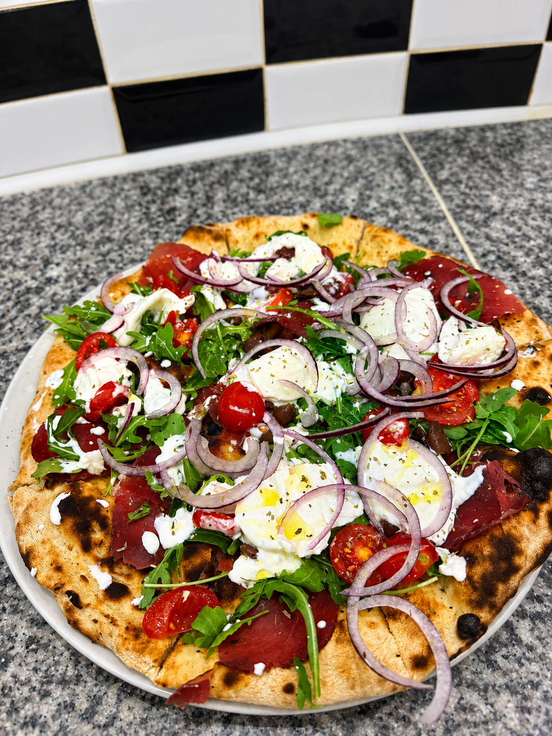 Focaccia con bresaola, rucola, burrata, pomodorini e cipolla rossa